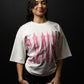Woman wearing a white t-shirt with pink and red graphics against a black background