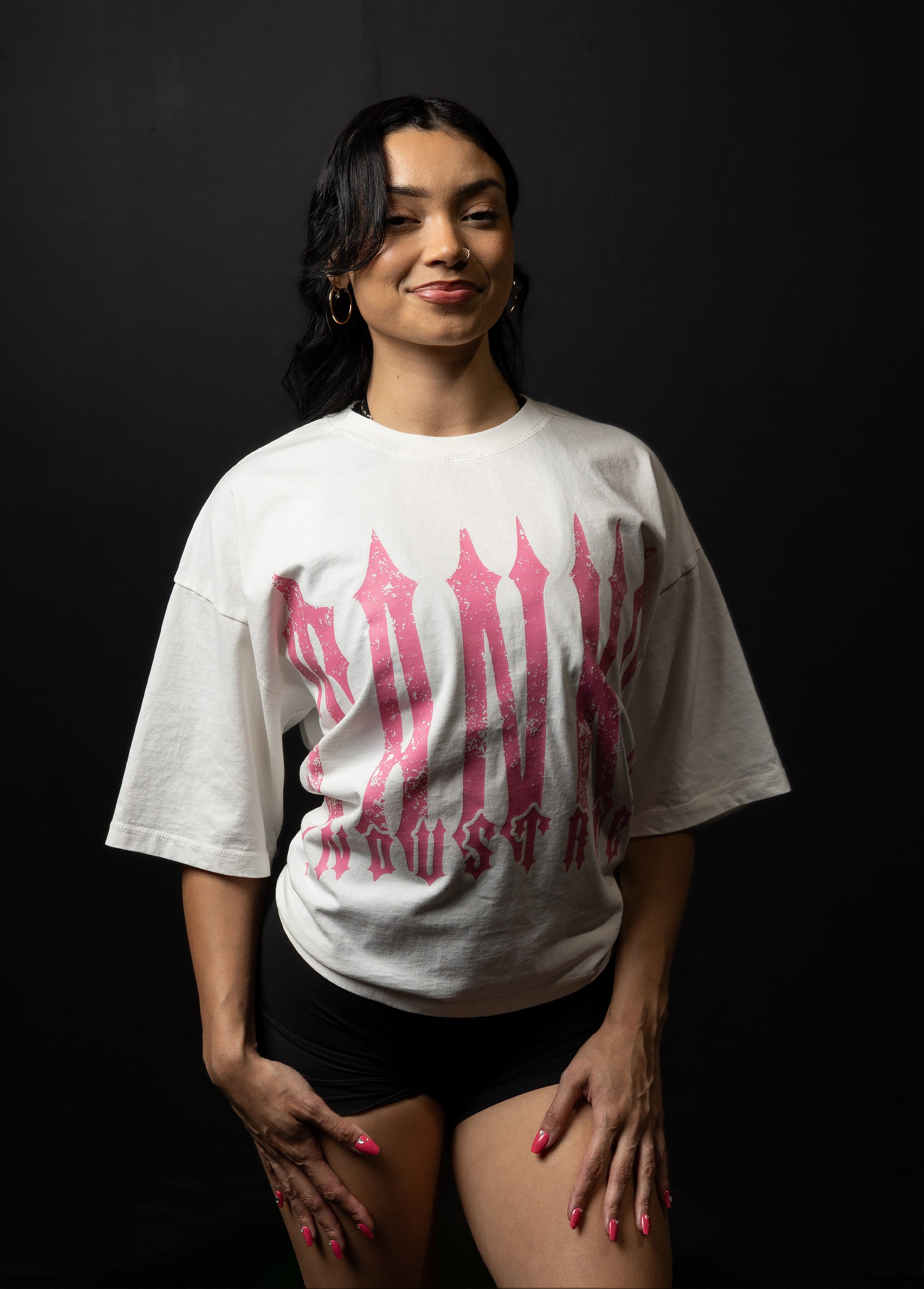 Woman wearing a white t-shirt with pink and red graphics against a black background