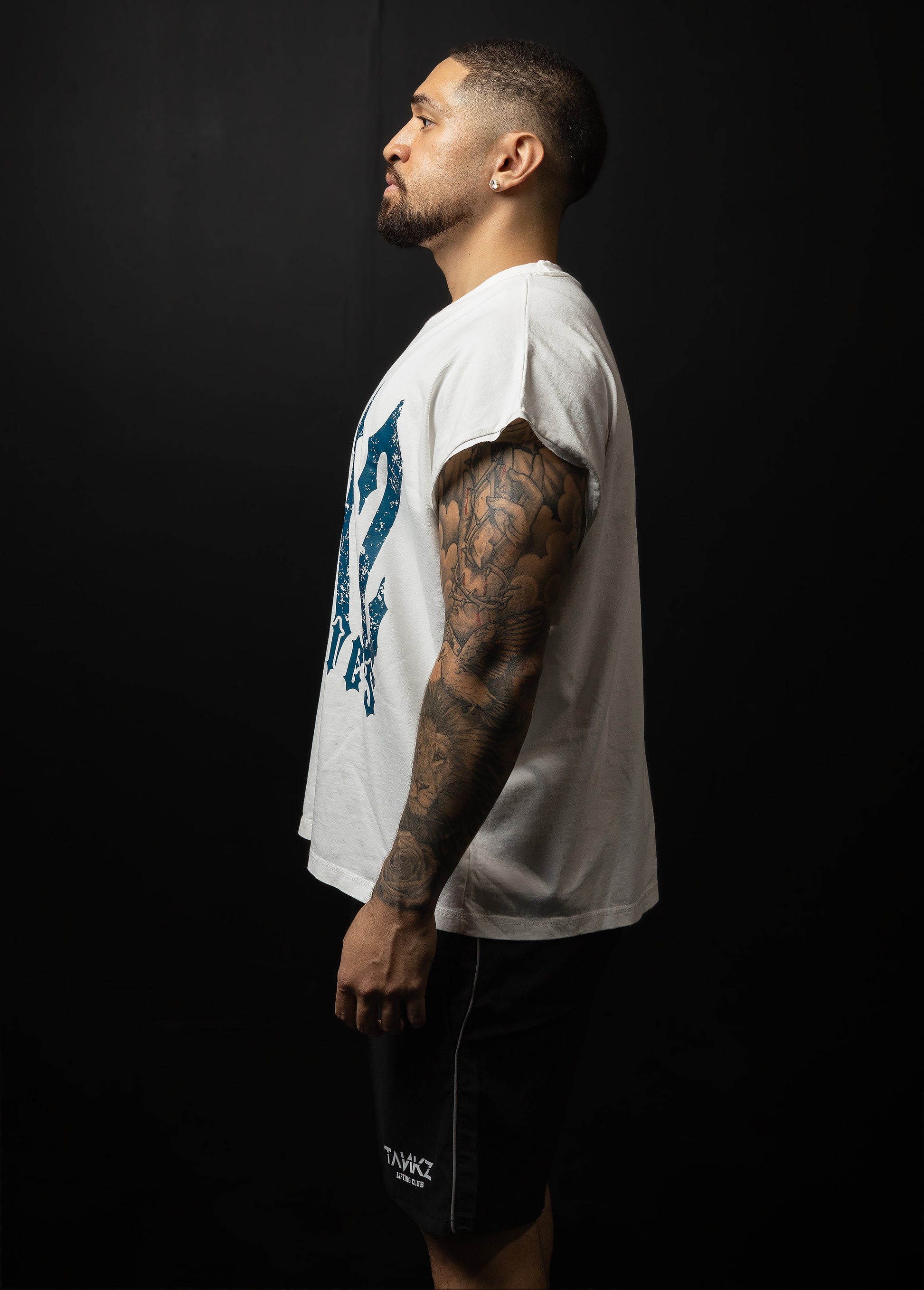 Man wearing a white t-shirt with text and black shorts on a dark background